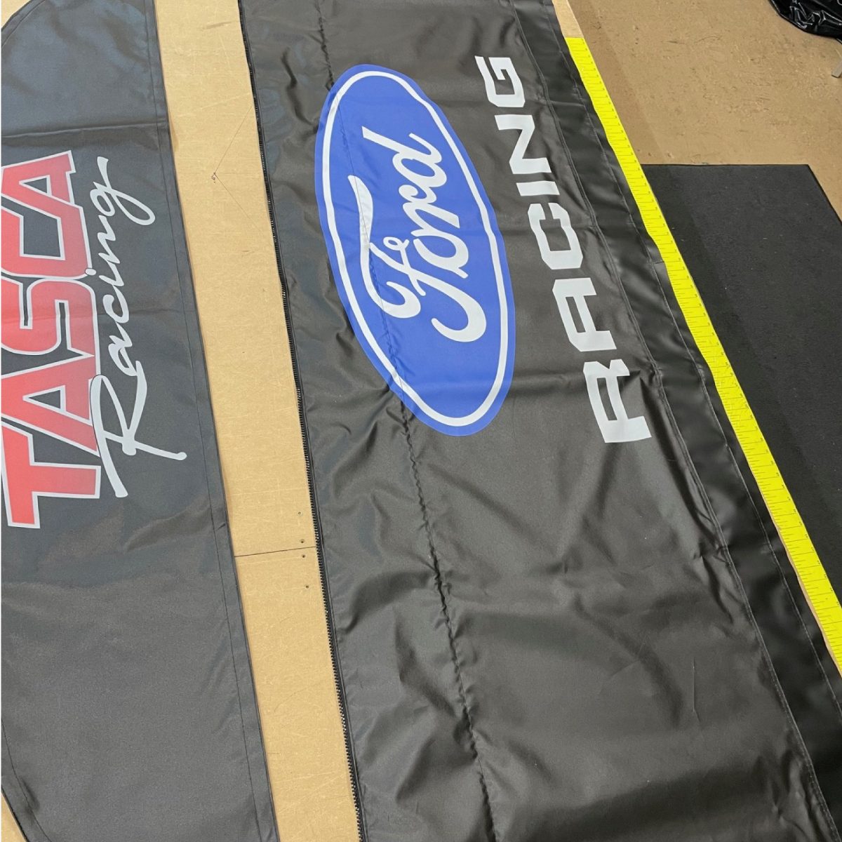 Tasca Racing and Ford Racing logos freshly printed on black awning fabric in the DMP print shop
